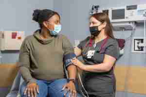 A doctor attends to a patient sitting in an exam room